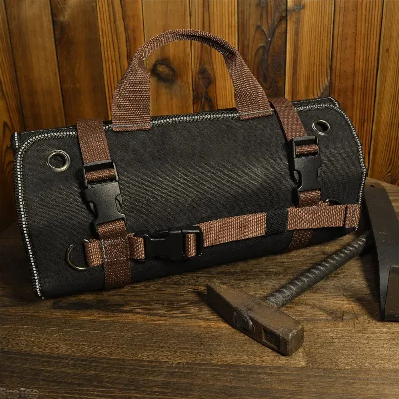 A rolled waxed canvas tool roll on a workbench beside a hammer